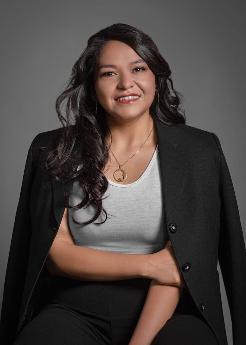 Portrait of Priya Nair smiling in a tailored dark blazer